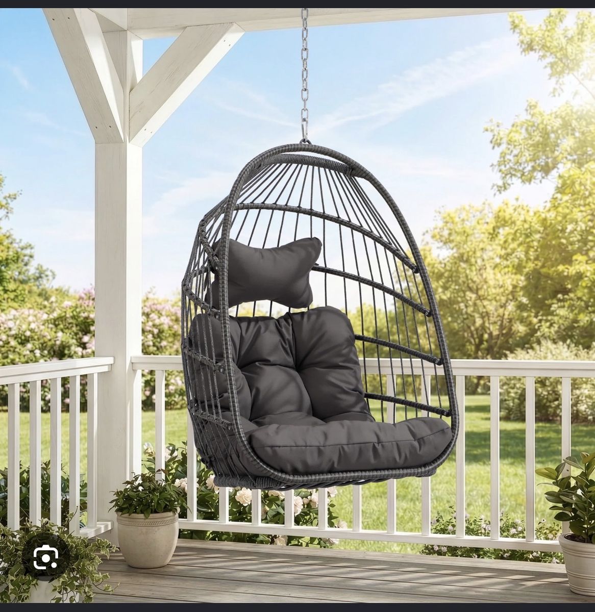 Hanging egg chair with maroon cushion and white pillow.