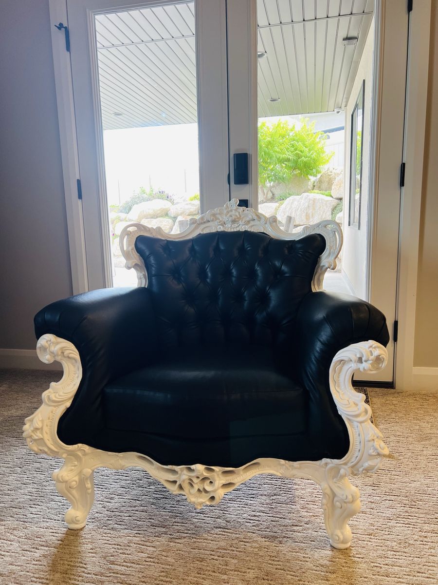 Black tufted faux leather chair with Victorian style carved white trim