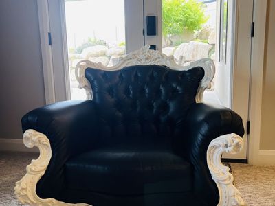 Black tufted faux leather chair with Victorian style carved white trim