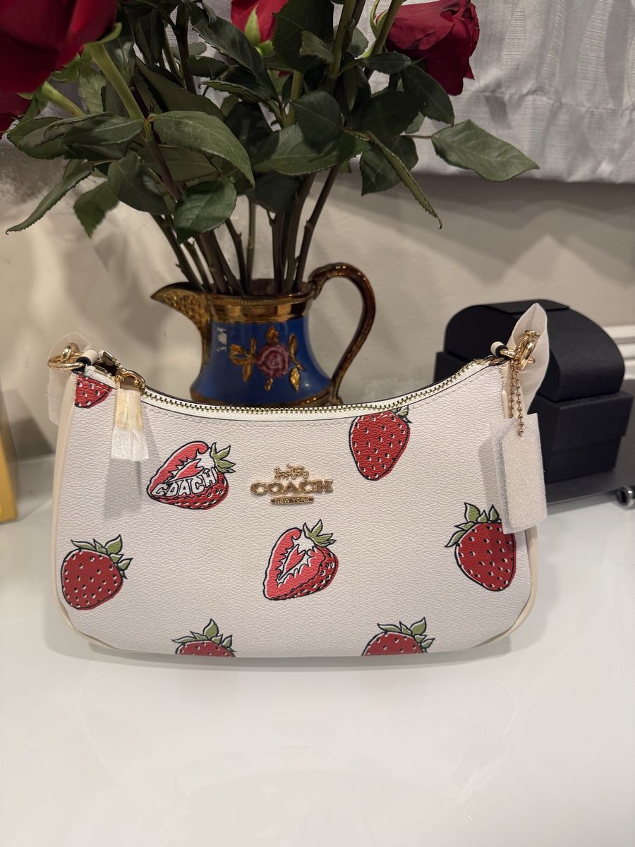 Coach leather tote with playful cherry motif. Red-accented handles and gold logo hardware. Structured silhouette suitable for da