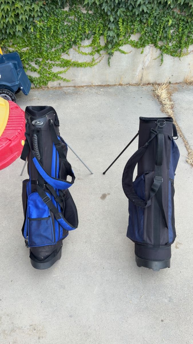 Two black and blue golf bags with stands.