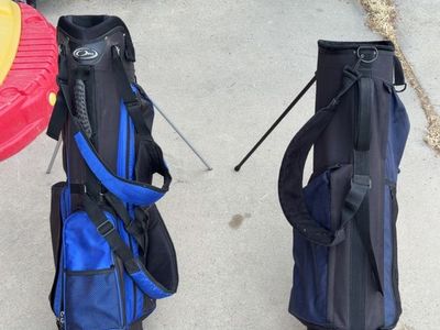 Two black and blue golf bags with stands.
