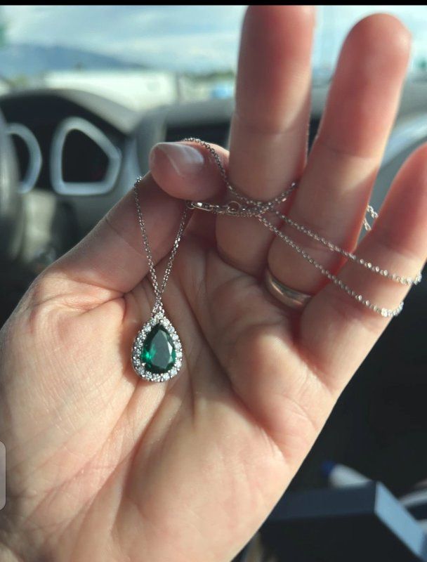 This Pear Emerald & 1/6 ct. tw. Diamond Halo Pendant in 14k white Gold chain is a stunning piece of fine jewelry.