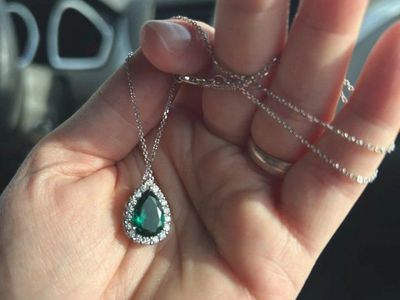 This Pear Emerald & 1/6 ct. tw. Diamond Halo Pendant in 14k white Gold chain is a stunning piece of fine jewelry.