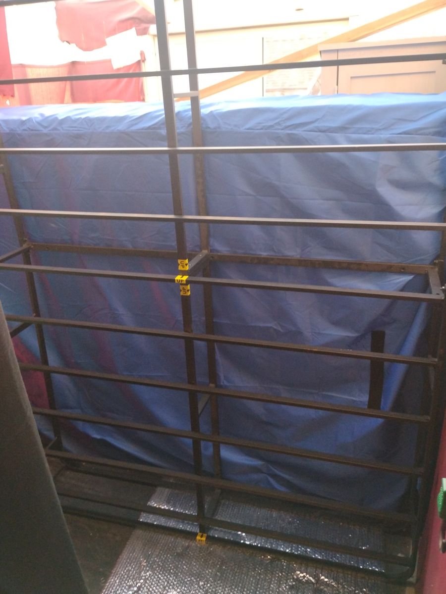 Metal box spring with a brand-new 12-inch mattress in a blue mattress moving bag