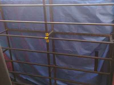 Metal box spring with a brand-new 12-inch mattress in a blue mattress moving bag