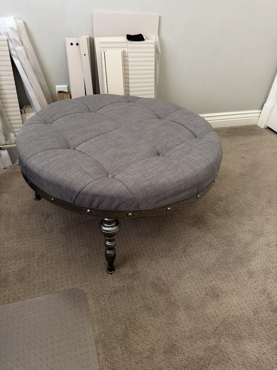Gray Tufted Round Ottoman with Decorative Nailhead Trim & Turned Legs
