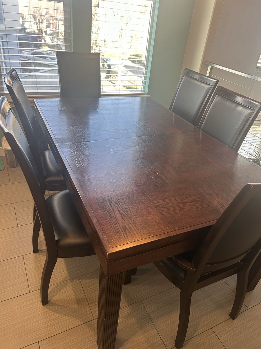 Solid wood dining table with 6 matching leather chairs and leaf extension.