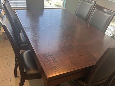Solid wood dining table with 6 matching leather chairs and leaf extension.