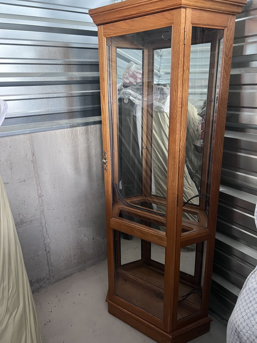 Solid oak curio cabinet with mirror and light inside .