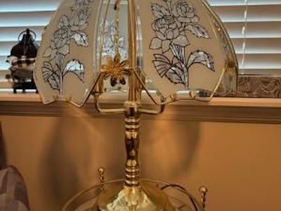 A vintage brass table lamp with a floral glass shade