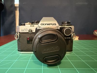 Olympus OM-10 SLR 35mm film camera w/ 50mm f/1.8 lens - manual adapter included.