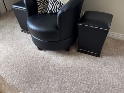 modern barrel chair with matching ottoman, upholstered in black faux leather (or bonded leather)