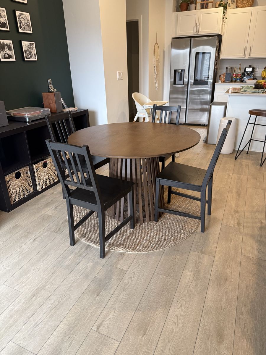 Round Dining Table with Wood Slat Base with 4 black chairs.