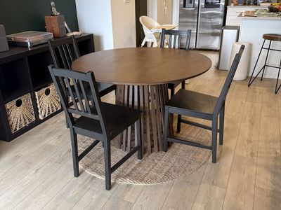 Round Dining Table with Wood Slat Base with 4 black chairs.