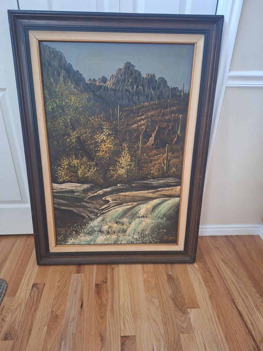 A mountain landscape with a waterfall and cacti oil painting with frame. 31.5" wide x 43.5" tall.