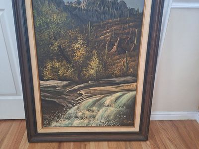 A mountain landscape with a waterfall and cacti oil painting with frame. 31.5" wide x 43.5" tall.