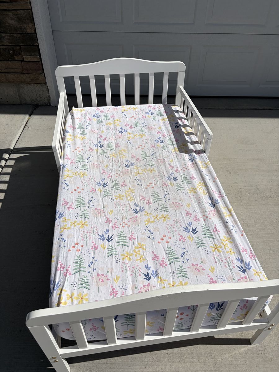 White toddler bed, mattress, & floral sheet