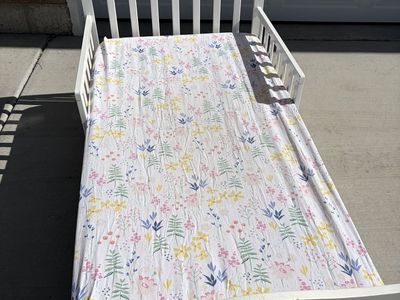 White toddler bed, mattress, & floral sheet