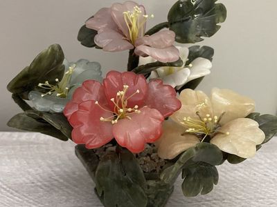 Vintage chinese jade peony plant features multi-colored blossoms dark green leaves in a pebbled pot
