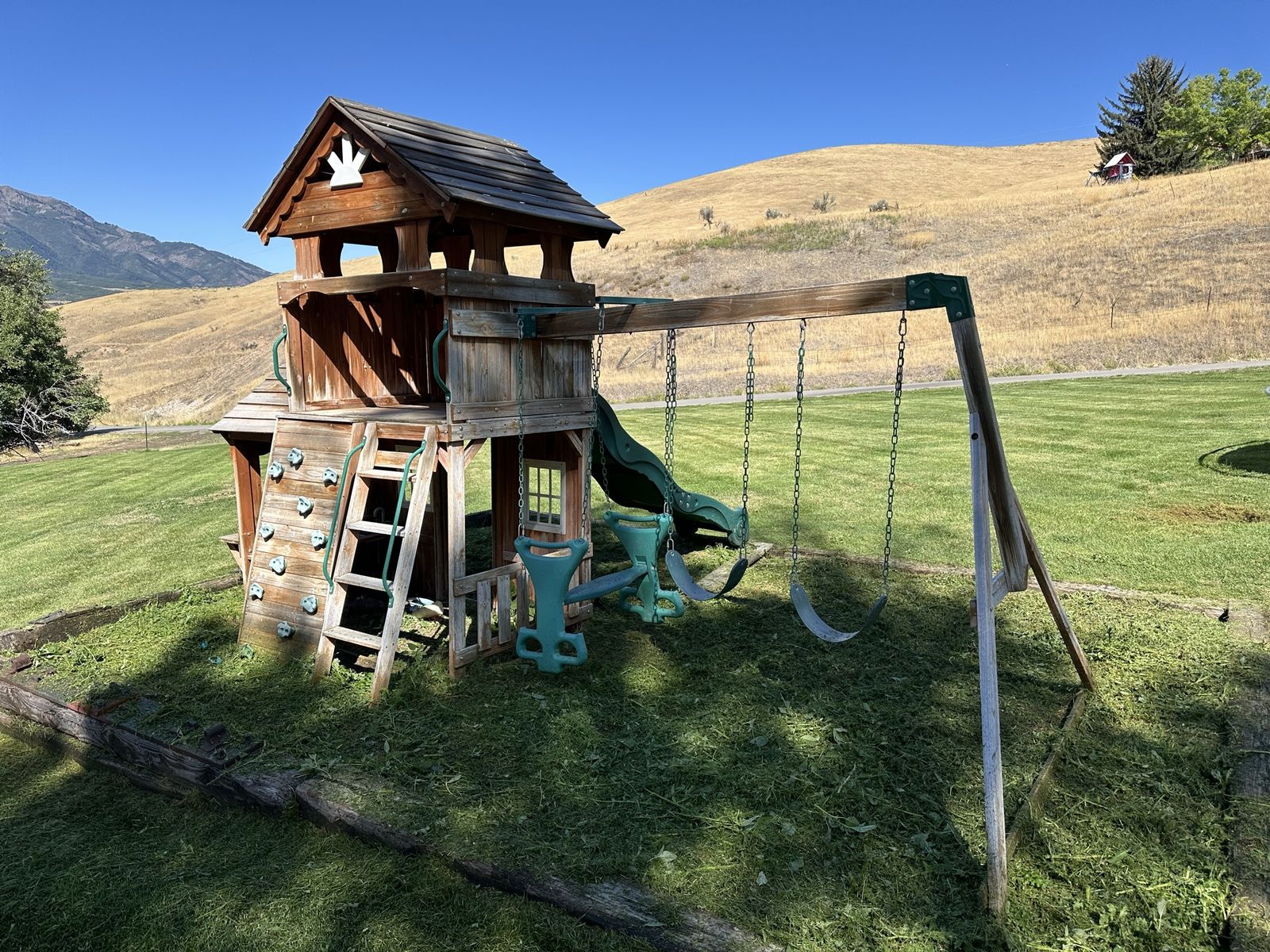 Wooden Play Set with Clubhouse, Swings, Slide, and Climbing Wall.