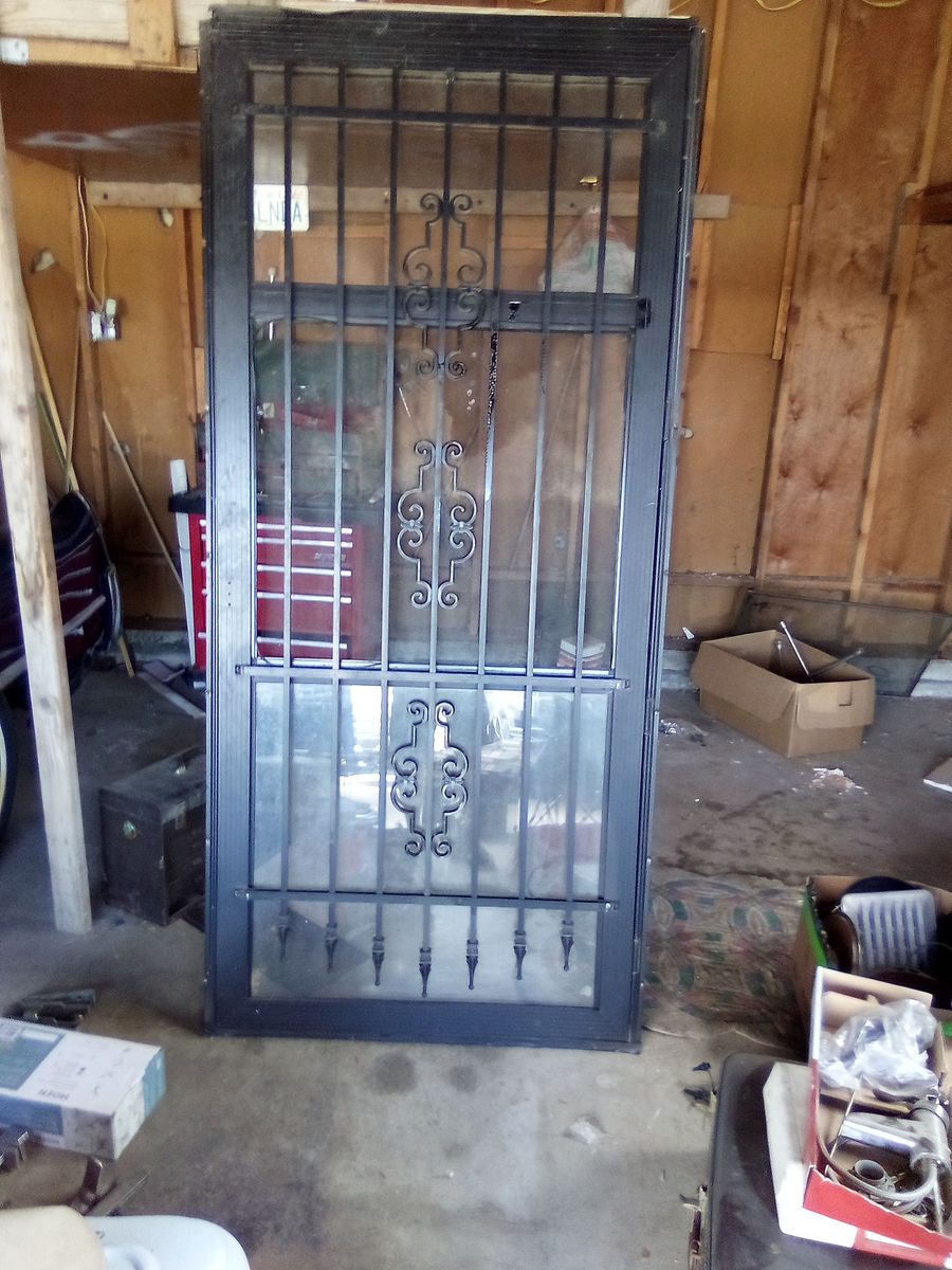 Vintage Brown Wooden Panel Door with Wrought Iron Insert and Black Security Storm Door