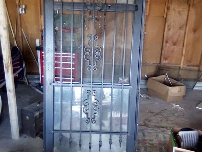 Vintage Brown Wooden Panel Door with Wrought Iron Insert and Black Security Storm Door