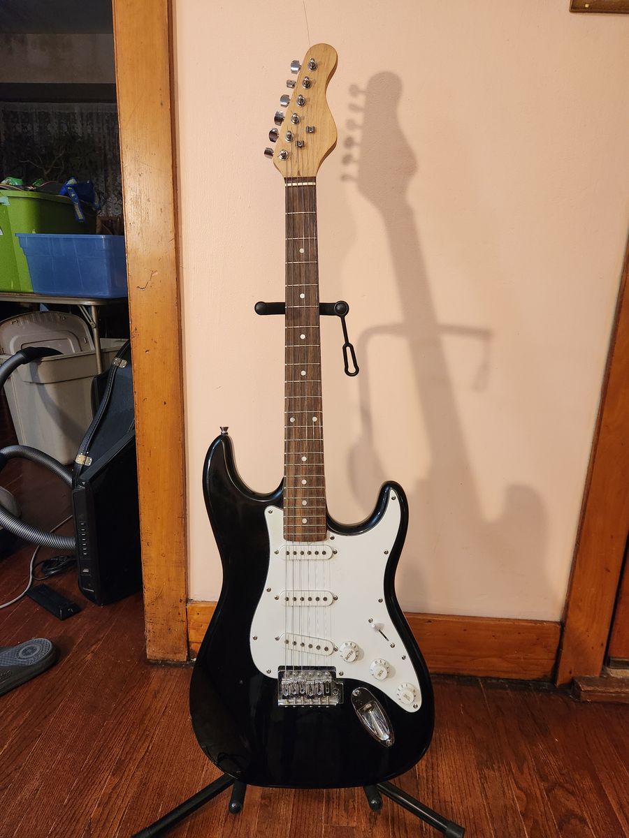 Full size Stratocaster electric guitar and two chords (one regular, the other an extension.)  No brand name.