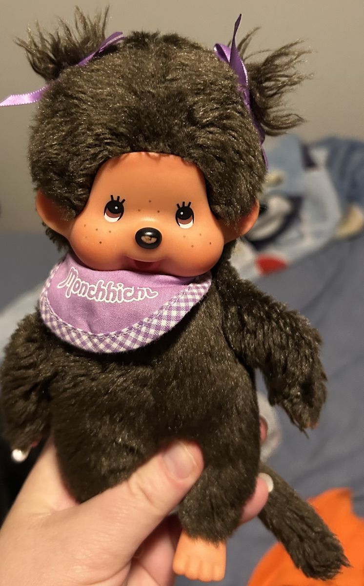 Sekiguchi Monchhichi plush doll featuring dark brown fur, twin tails with purple ribbons