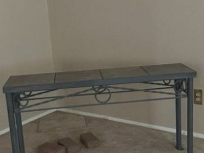 Iron table with stone tiles on top. Compliments the back of sofa or wall as well.