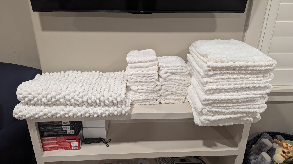 Beautiful white bathroom towels and 2 rugs.