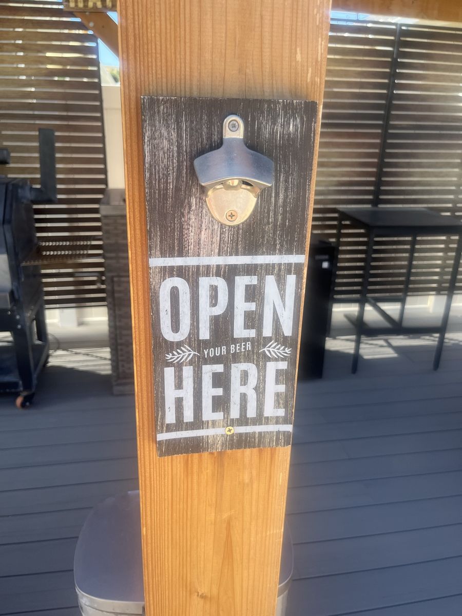 Rustic wall-mounted bottle opener with a dark-stained wooden plaque
