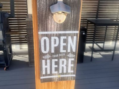 Rustic wall-mounted bottle opener with a dark-stained wooden plaque