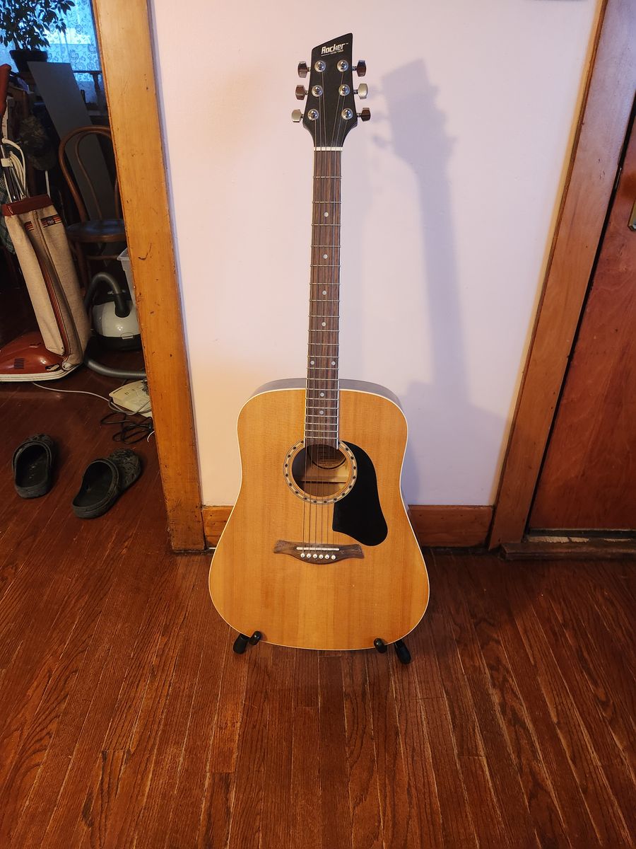 Rocker Model RA-200 acoustic dreadnaught sized guitar, guitar stand, Ibanez bag, guitar strap...and a pick.  Sounds/looks great.