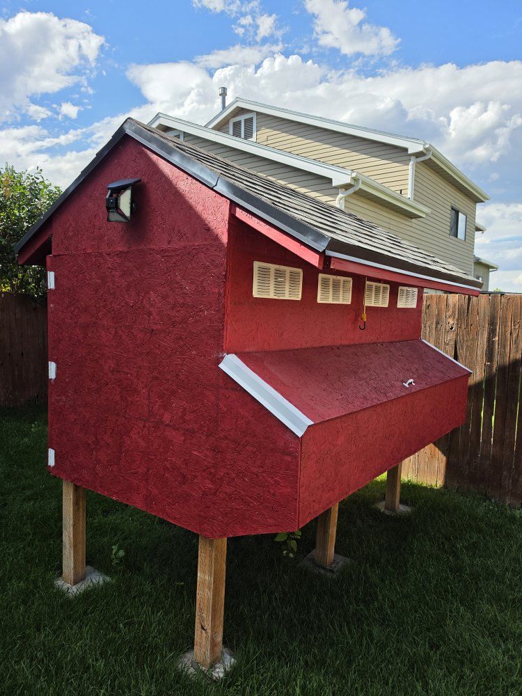 Custom Built Wooden Chicken Coop in Red with Shingled Roof and Elevated Design
