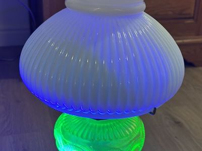 Vintage Aladdin brand oil lamp featuring a "Washington Drape" pattern base made of uranium glass.