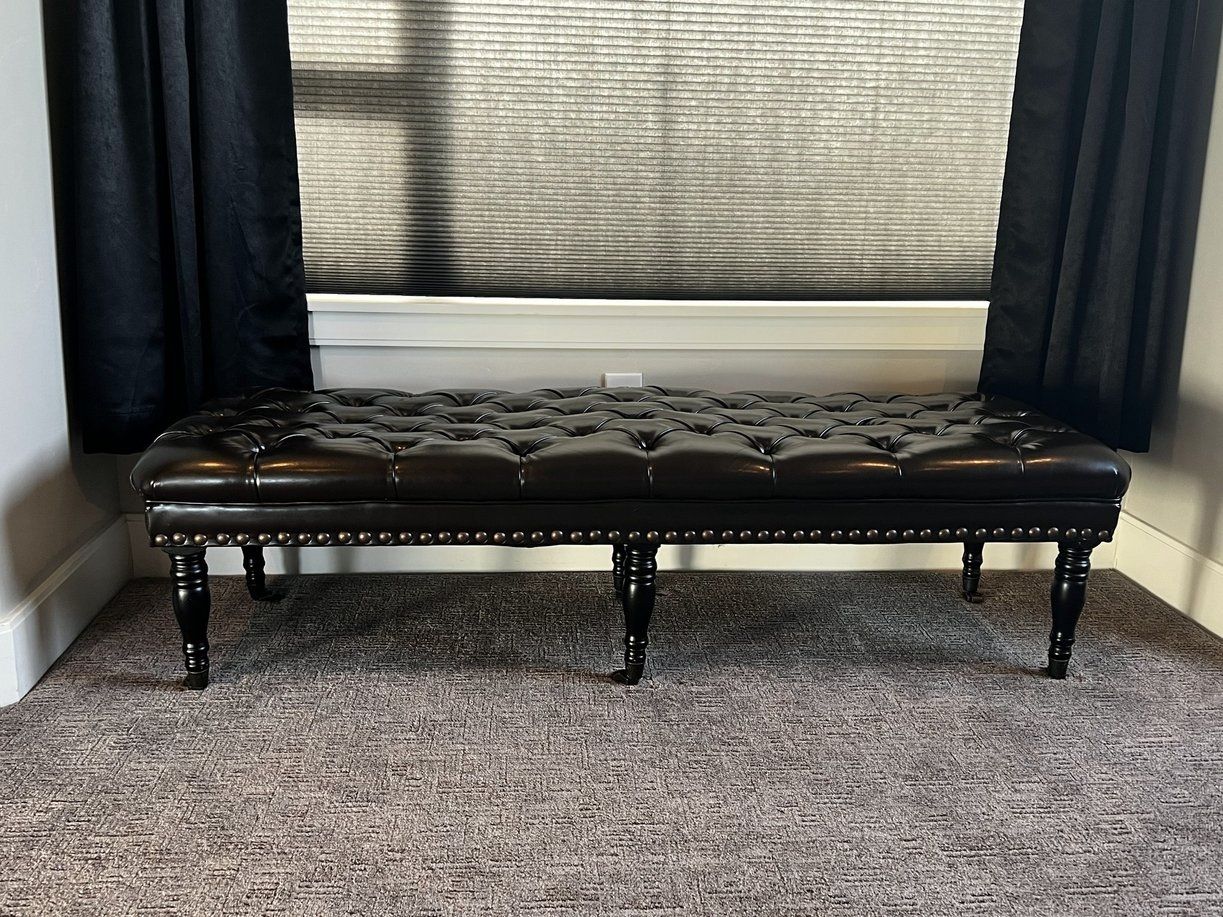 Leather upholstered bench with nailhead trim on casters