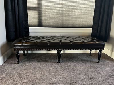 Leather upholstered bench with nailhead trim on casters