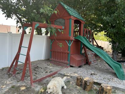 Playhouse with slide, monkey bars, climbing wall and space for swings.