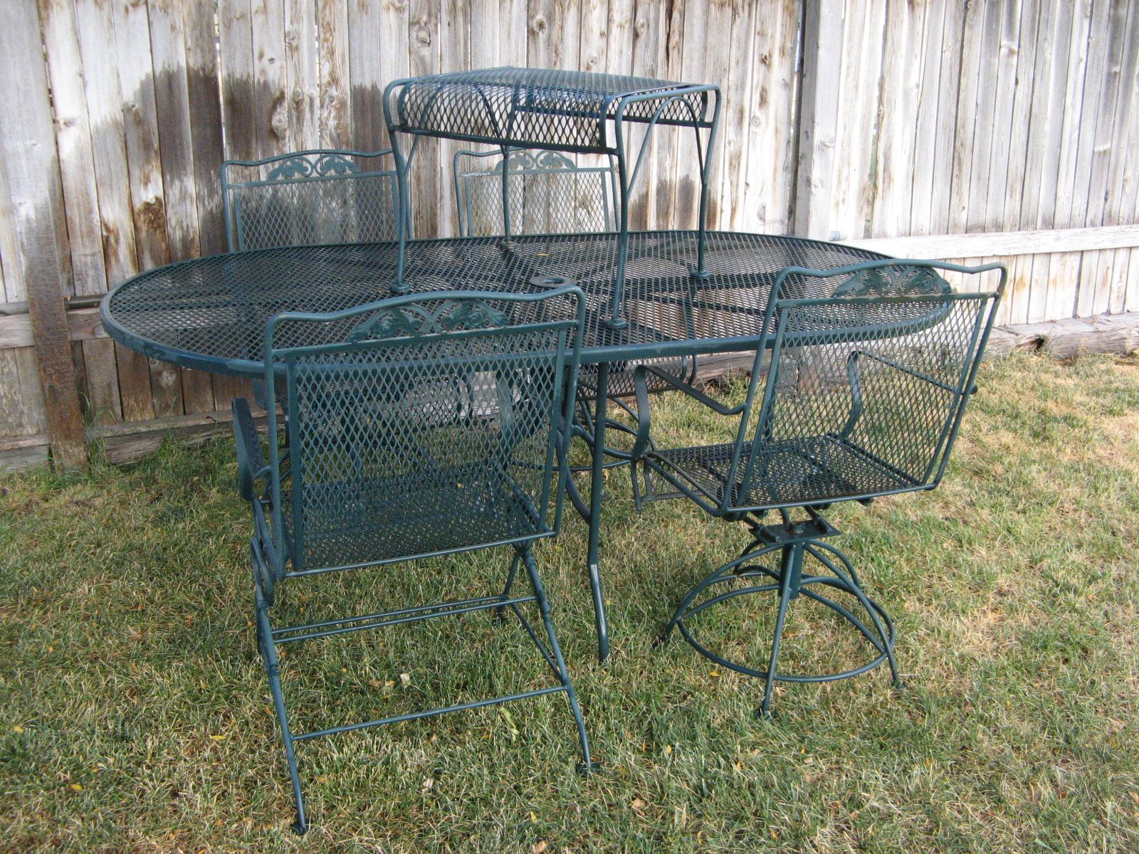 Vintage 6 piece wrought iron patio set, 6 foot oval table, 4 coil spring ornate bounce/rocker arm chairs & a foot rest. NICE