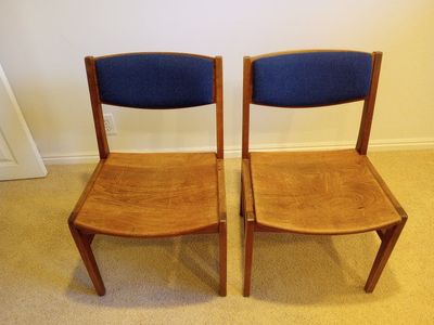Two matching hardwood chairs with padded cloth backs.