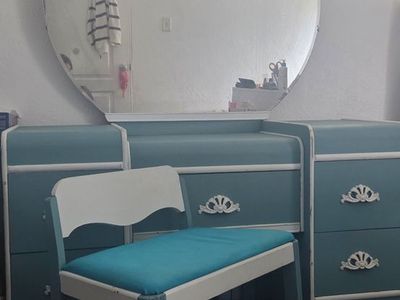 Antique vanity with mirror and chair and chest.