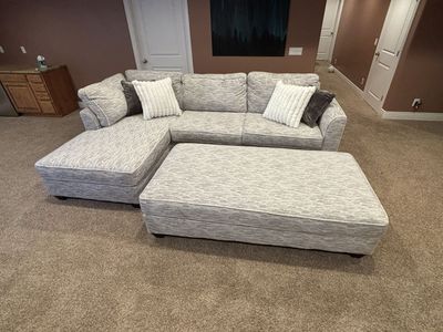 Light Gray Textured Sectional Sofa with Matching Ottoman and Pillows
