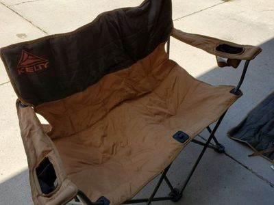 Kelty Loveseat Camp Chair in tan and black. It's a double folding outdoor seat with two cup holders.