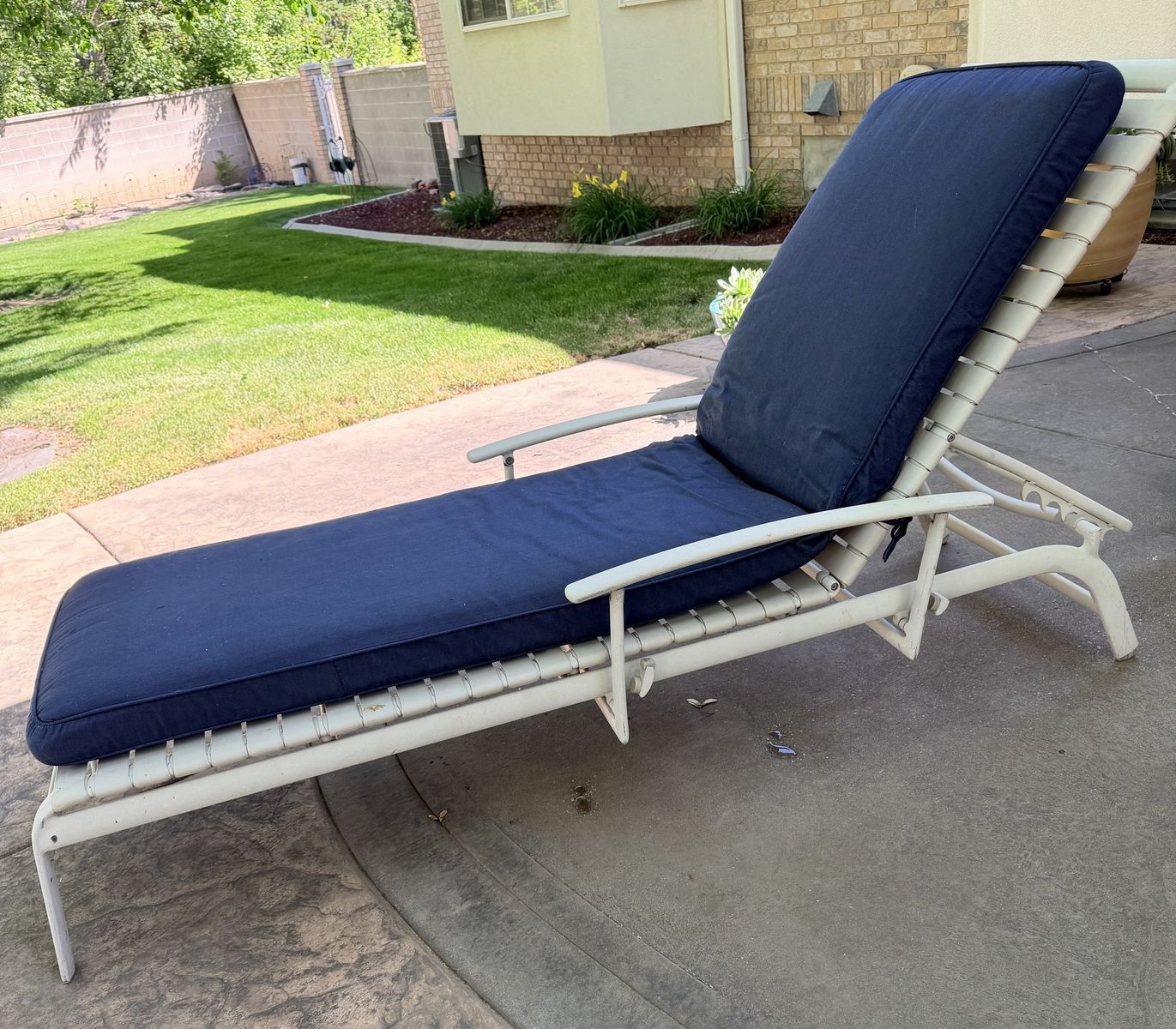 Made To Last, powder-coated, metal patio chaise lounge equipped with a plush, navy blue cushion.
