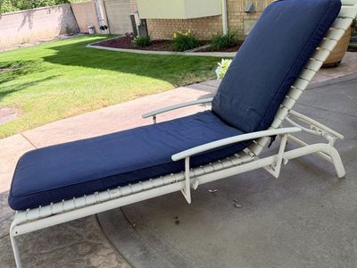 Made To Last, powder-coated, metal patio chaise lounge equipped with a plush, navy blue cushion.