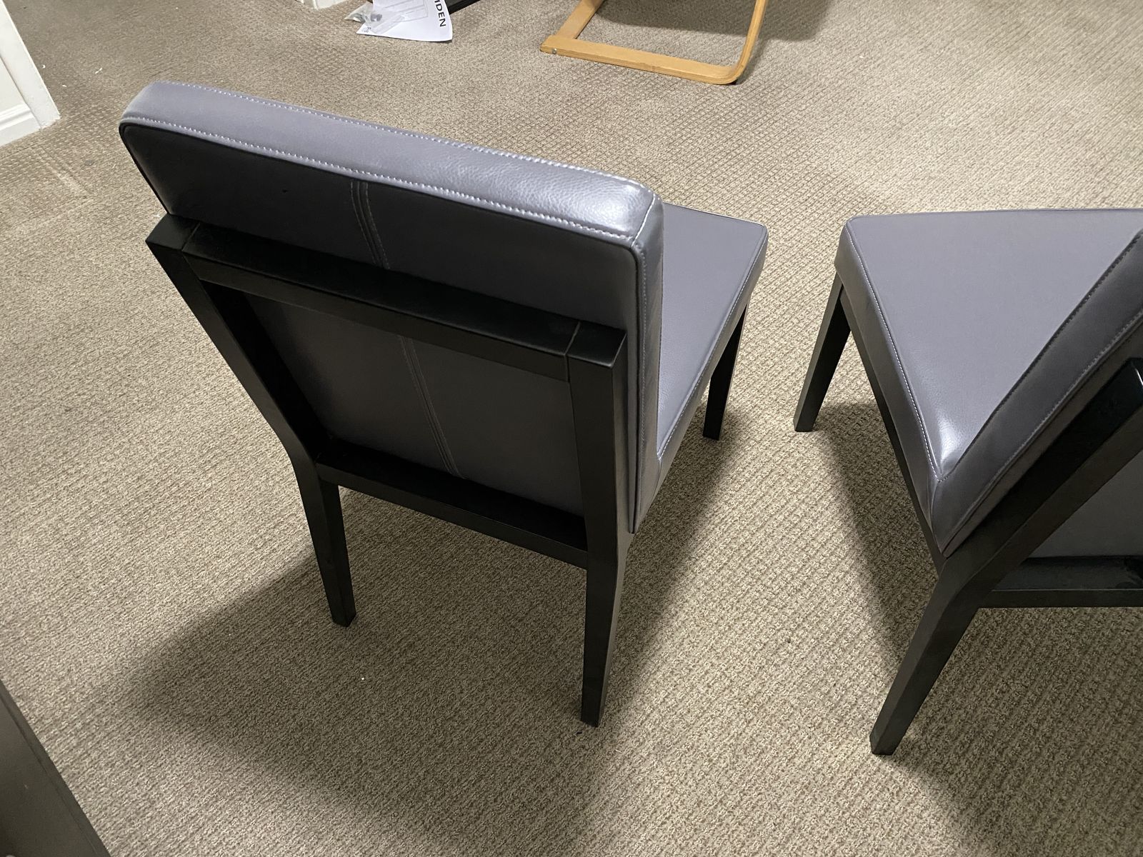 Two gray leather chairs with wooden frames