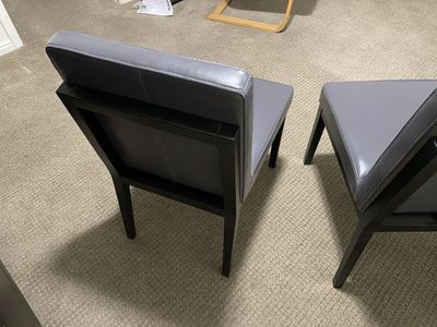 Two gray leather chairs with wooden frames