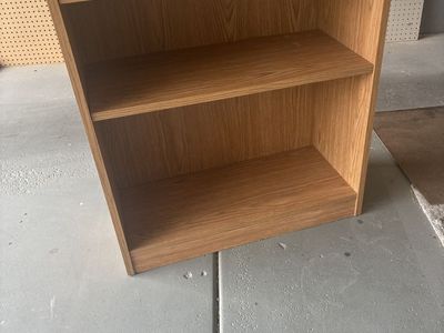 Small light brown bookcase with shelf