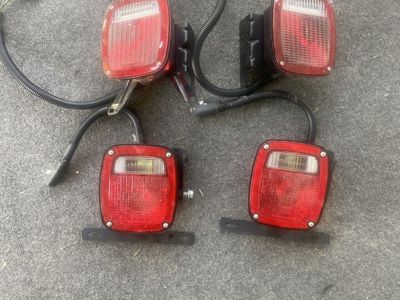 Set of 4 Red Trailer Taillights with Wiring Harnesses and Mounting Brackets.